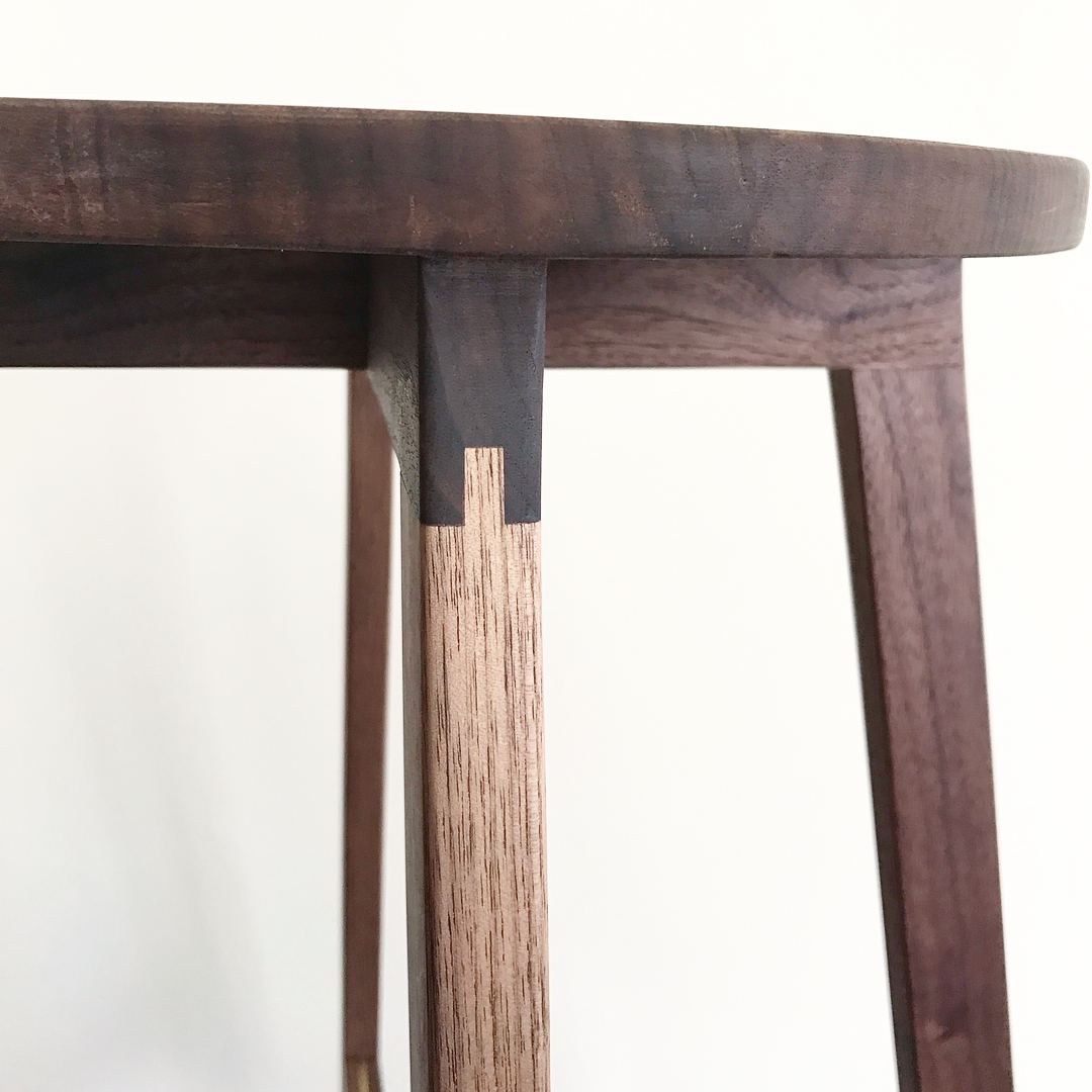 Close-up of a walnut leg joined to the underside of the seat