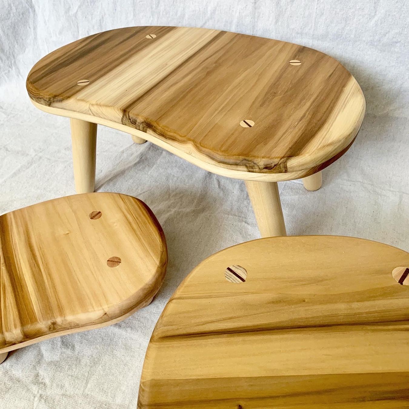 Close-up of the poplar stool seats, showing the wood grain and the wedged leg tenons coming through the top
